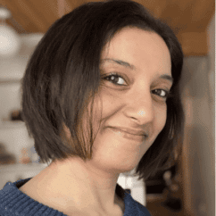 Neetal Parekh smiling at the camera against a wooden background.